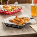 A black rectangular plastic fast food basket filled with food on a table.