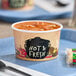 A white Choice double poly-coated paper soup container filled with soup on a plate.