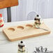 An Acopa natural wood flight tray with desserts in jars on a table.