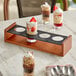 A table with a group of Acopa Walnut Finish Drop-In Flight Carriers holding desserts in glasses.