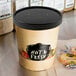 A Choice paper soup cup with a black lid filled with hot food.