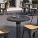 A round blue galaxy quartz table top on a table with chairs and a candle.