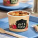 A Choice paper soup cup filled with meat and vegetable soup on a tray.