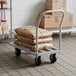 A Regency mobile aluminum dunnage rack with a stack of bags on it.