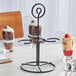 An Acopa black metal stand holding three dessert glasses.