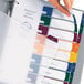 A hand holding a file folder with colorful Avery Ready Index dividers inside.