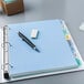 A white file folder with colorful tabs on a blue surface with a pen and eraser.