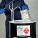 A man in a blue uniform pouring liquid into a barrel using Avery UltraDuty GHS labels.