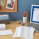 A laptop on a desk with Avery White Mailing Address Labels on a stack of white paper.