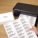 A person using a printer to print Avery white mailing address labels.