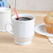 A Tuxton bright white china mug with a straw in it.