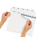 A pair of hands using Avery Index Maker dividers to label a piece of paper.