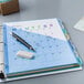 A file folder with Avery 8-tab plastic dividers with a calendar and pen on top.
