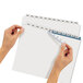 A person using Avery Index Maker white divider tabs to label a file folder with a pen.