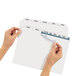 A pair of hands using Avery Big Tab dividers to label a file folder.
