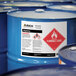 A group of blue barrels with Avery UltraDuty GHS labels on them.