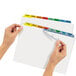 A pair of hands holding a file folder with Avery 8-tab multi-color divider labels.