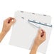A pair of hands using Avery Index Maker dividers to label a file folder.