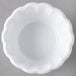 A close-up of a white Carlisle ramekin with a scalloped edge.