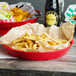 A table with two red Choice diner platters filled with french fries and a bottle of beer.