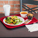 A Vollrath red plastic fast food tray with a plate of salad, a muffin, and a cup of soup on it.