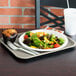 A Vollrath almond plastic fast food tray with a plate of salad and a muffin.