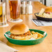A green Choice plastic diner platter with a sandwich and fries.