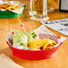 A red Choice plastic diner platter with food in it on a table.