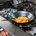 A black Town French style carbon steel fry pan with food on top of a stove.