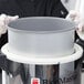 A person in gloves holding a Teflon-coated aluminum Town rice cooker pot.