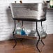 A Tablecraft stainless steel beverage tub on a shelf with wine and glasses inside.