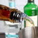 A person using a Tablecraft Proper Pour clear spout to pour liquid into a glass.