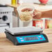 A person using an AvaWeigh digital portion scale to measure pasta in a plastic container.