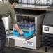 A man putting glasses in a Jackson DishStar undercounter dishwasher.