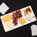 An American Metalcraft white flat melamine platter with cheese, grapes, and crackers on it.