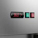 A stainless steel reach-in refrigerator with a digital temperature display and control panel featuring green and red power switches.