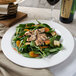 A Villeroy & Boch white porcelain round platter with salad and meat next to a glass of wine.