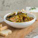 A Villeroy & Boch white porcelain bowl filled with pickles on a wooden surface.