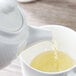 A white Villeroy & Boch teapot pouring tea into a cup.