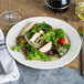 A Villeroy & Boch white porcelain plate with salad, chicken, and vegetables on it.