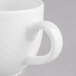 A close-up of a Villeroy & Boch white porcelain cup with a handle.