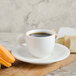 A white Villeroy & Boch porcelain cup of coffee on a saucer with macarons.