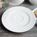 A person holding a Villeroy & Boch white porcelain saucer with a cup over a plate.