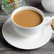 A white porcelain saucer with a cup of coffee and a cookie.