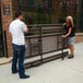 A man and woman setting up a Lifetime rectangular plastic picnic table with attached benches.