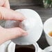 A person pouring tea into a white Villeroy & Boch teapot.