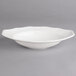 A white porcelain oval deep plate with a scalloped edge.