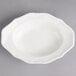 A white porcelain oval deep plate with a scalloped edge.