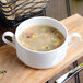 A white Villeroy & Boch La Scala porcelain soup cup filled with chicken and vegetable soup.