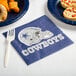 A blue plate with a Creative Converting Dallas Cowboys luncheon napkin on it, with food.